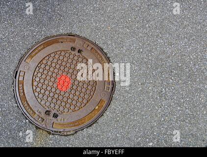 cast-iron sewer cover with red point Stock Photo