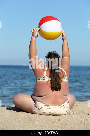 overweight woman doing gymnastics on beach Stock Photo