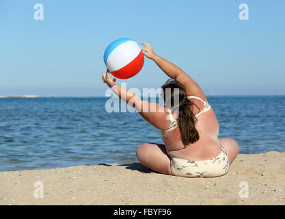 overweight woman doing gymnastics on beach Stock Photo