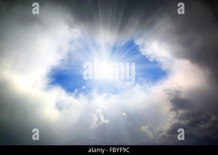 sun shining through hole in clouds Stock Photo