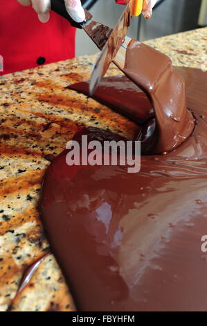 Food Sweets Chocolate making woman tempering chocolate on a cold marble table Stock Photo