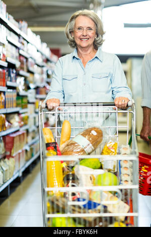 Smiling senior woman pushing cart Stock Photo