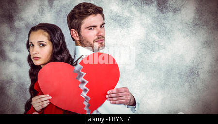 Composite image of couple back to back holding heart halves Stock Photo