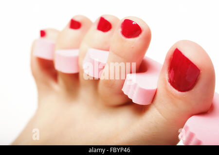 Woman applying red nail varnish to her toenails using an applicator ...
