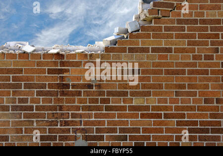 Crumbling brick wall with wispy clouds in blue sky. Stock Photo