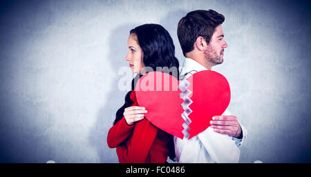 Composite image of couple back to back holding heart halves
