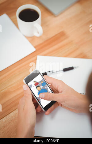 Composite image of businessman using smartphone at desk in office Stock Photo