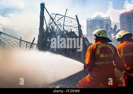Firefighters cooling down a burnt warehouse in Jakarta, Indonesia. Stock Photo