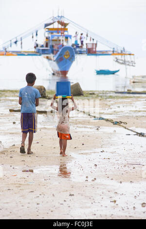 Fishing vessel with outriggers at low tide by the village of