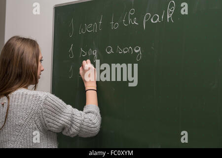 Teenager writes in English on the blackboard
