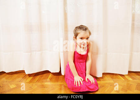 Little girl in red dress on floor Stock Photo