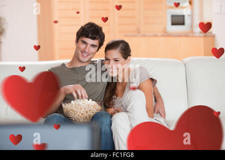 Composite image of couple with popcorn on the sofa watching a movie Stock Photo