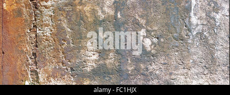 Old rusty colored wall in small old alley, with vertical cracked lines, one shows inside bricks. Stock Photo