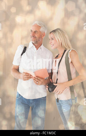 Composite image of happy tourist couple using the guidebook Stock Photo