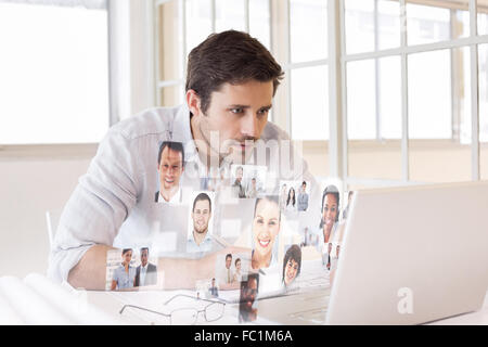 Composite image of businessman working on blueprints and laptop in office Stock Photo