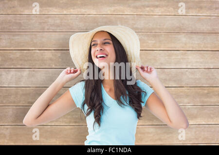 Composite image of happy young brunette wearing sunhat Stock Photo