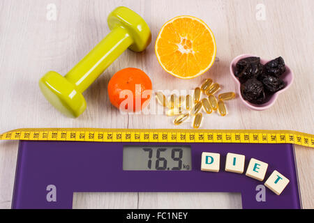 Tape measure on household digital bathroom scale for weight of human body, dumbbells for fitness, fresh fruits Stock Photo