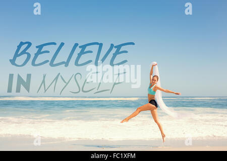 Composite image of fit woman jumping gracefully on the beach with scarf Stock Photo