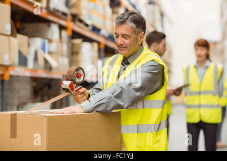 Warehouse worker sealing cardboard boxes for shipping Stock Photo