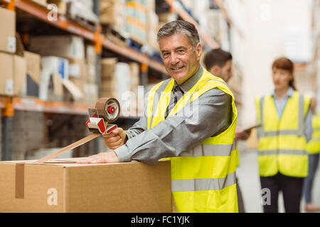 Warehouse worker sealing cardboard boxes for shipping Stock Photo