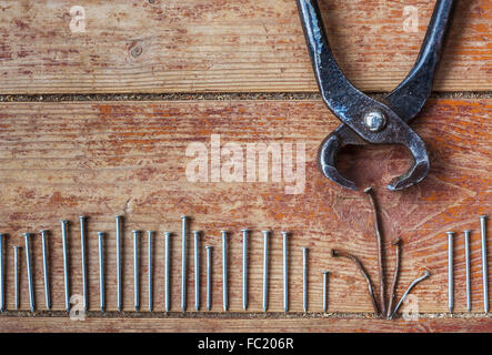 Stages of repair at home - to pull out the old nails. Pliers and old bent nails with new ones on the background of floor Stock Photo