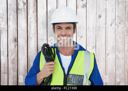 Composite image of confident electrician with wire against white background Stock Photo