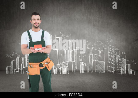 Composite image of happy construction worker holding house model Stock Photo