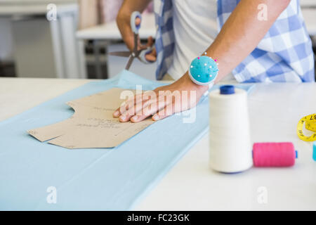 Fashion student cutting fabric with pair of scissors Stock Photo