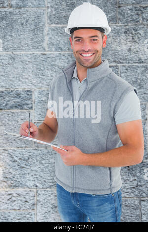 Composite image of portrait of smiling supervisor writing on clipboard Stock Photo