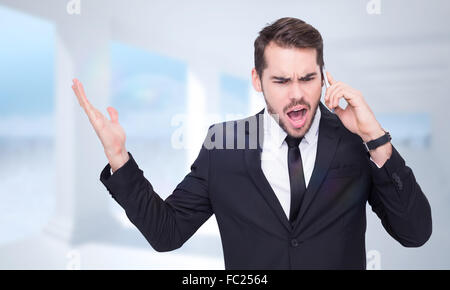 Composite image of angry businessman gesturing on the phone Stock Photo
