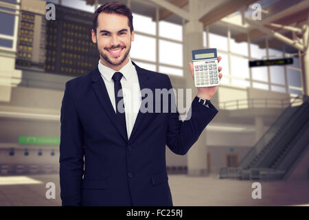 Composite image of smiling businessman presenting a calculator Stock Photo