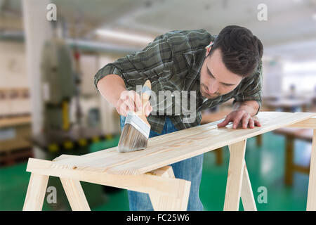 Composite image of worker using brush on wooden plank Stock Photo