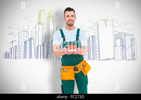 Composite image of happy construction worker holding house model Stock Photo