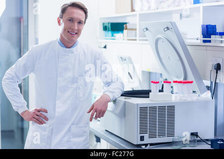Smiling chemist leaning against the centrifuge Stock Photo