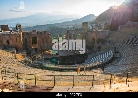 Taormina Greek theatre, view at sunset of people walking across the ancient Greek theatre (Teatro Greco) Taormina, Sicily. Stock Photo