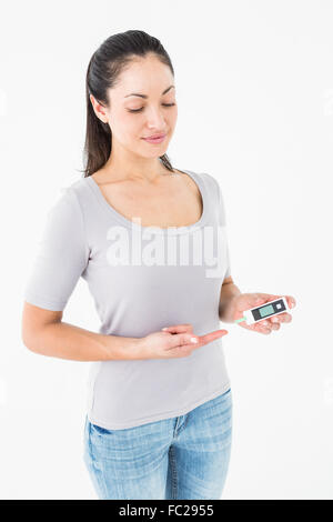 Diabetic brunette holding blood glucose monitor Stock Photo