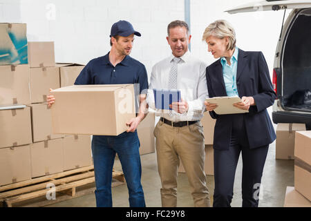 Delivery driver checking his list on tablet with managers Stock Photo