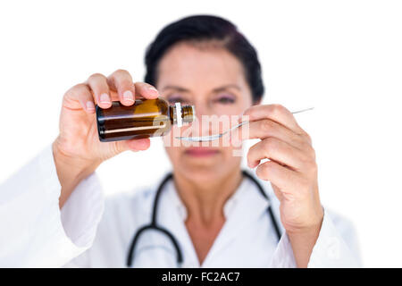 Confident female doctor pouring syrup in a spoon Stock Photo