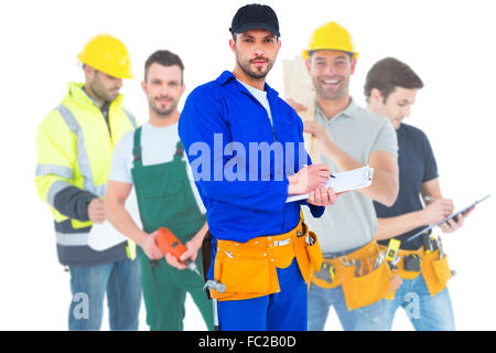 Composite image of handyman in blue overall writing on clipboard Stock Photo