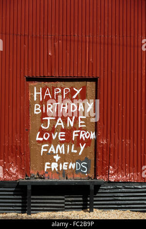 Hand painted birthday wishes written on an a door of a red abandoned building. Stock Photo