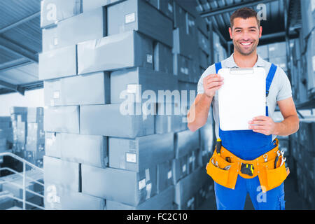 Composite image of portrait of happy repairman showing blank clipboard Stock Photo