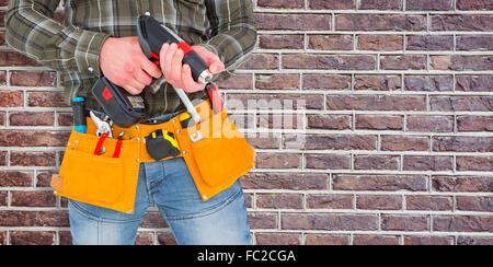 Composite image of manual worker holding gloves and hammer power drill Stock Photo