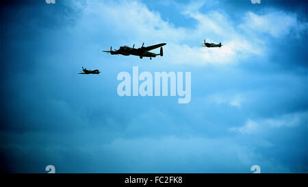 Lancaster Bomber with Hurricane and Spitfire escort against a dark blue cloudy sky shot look like night time, moon light atmospheric image editorial Stock Photo