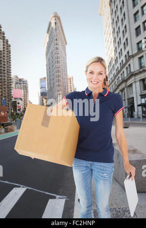 Composite image of happy delivery woman holding cardboard box and clipboard Stock Photo
