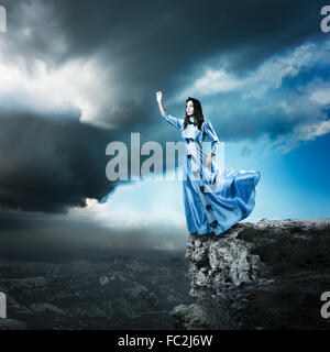 Woman in Blue Dress Reaching for the Light Stock Photo