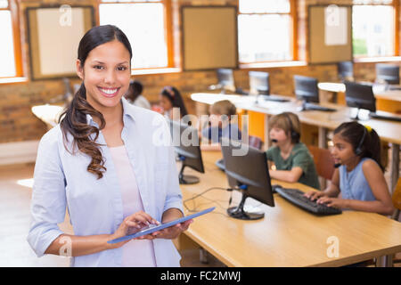 Pretty teacher and pupil using tablet at his desk Stock Photo - Alamy