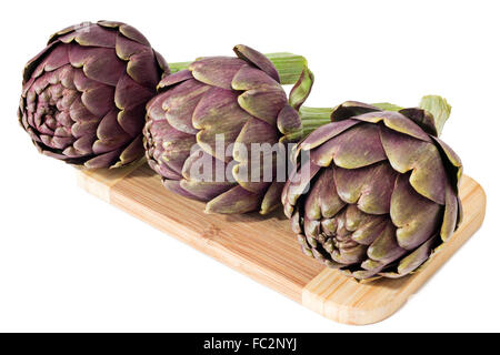 Three artichokes on a cutting board Stock Photo