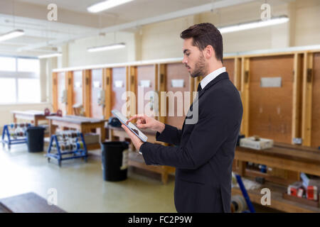 Composite image of concentrated businessman touching his tablet Stock Photo