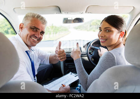 happy woman taking driving lessons from instructor and giving thumbs up Stock Photo