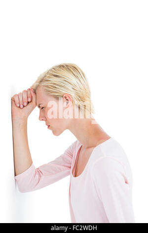 Nervous blonde woman leaning against the wall Stock Photo